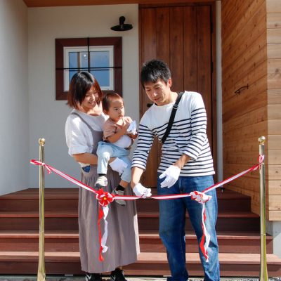 引渡しの日、家の前でテープカットをするオーナー