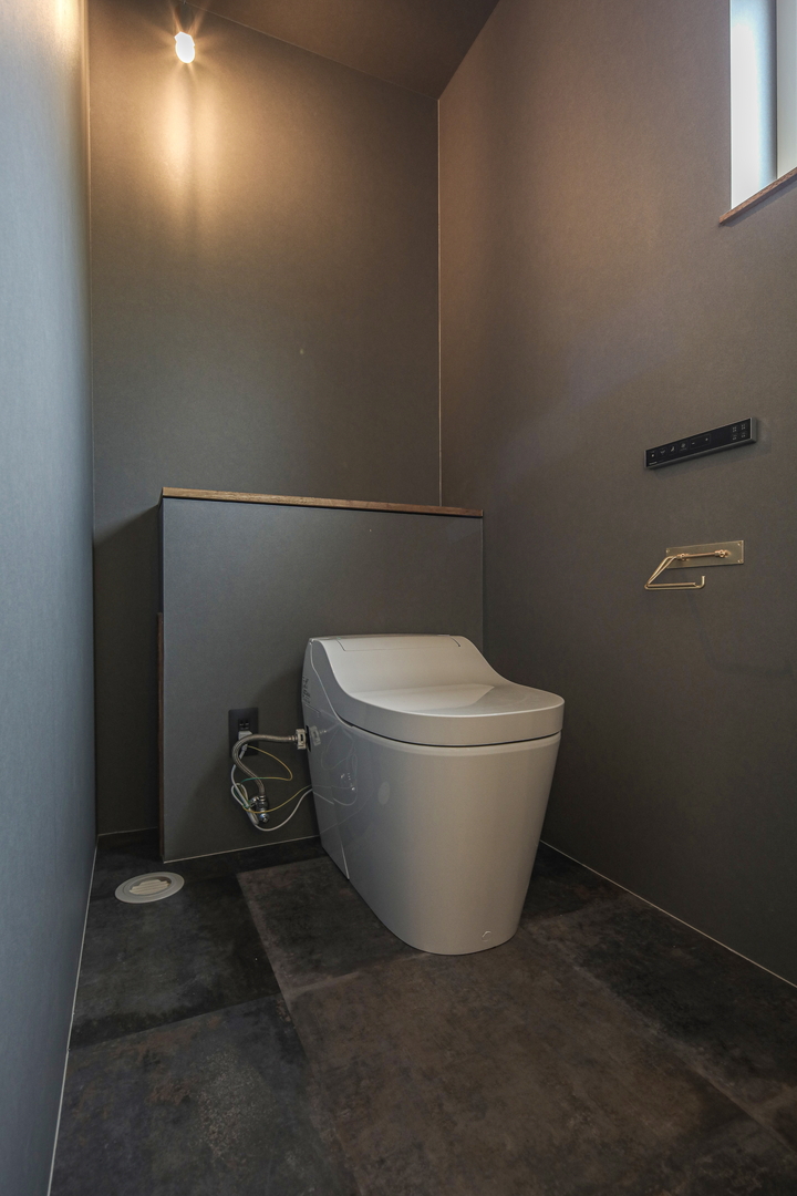 グレーでまとめた内観に真鍮が光るトイレ