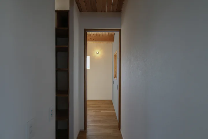 2階の廊下から主寝室を見る。壁付けの真鍮照明が静かに暖かい雰囲気を創ってくれる。