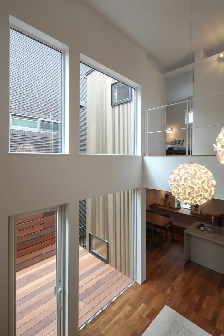 吹抜け階段からリビング側を見ている。吹抜けの南側には高い位置に窓を設けているので、隣地があっても光が入る。