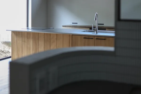 手前には造作洗面台の腰壁、タイルが貼られている。奥にはウッドワンのキッチン。腰壁の無いパーティータイプで天板はステンレス"