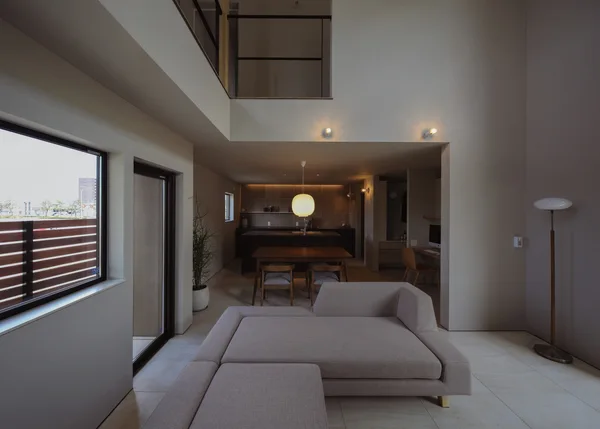 手前からリビング、ダイニング、キッチンが一直線につながっている。リビングにはグレーのソファ。ダイニングセットは椅子が4脚あり、四角いテーブルの上にはルイスポールセンの丸い乳白色のガラスペンダントライトが釣り下がっている。その奥にはオープンなキッチンが見える。