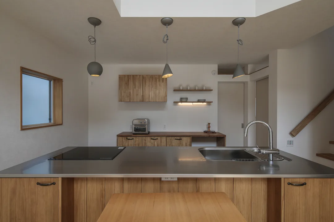 キッチン。ウッドワンのパーティータイプ。キッチン上にはペンダントライトが3灯。キッチン背面にカップボードと吊戸棚、飾り棚