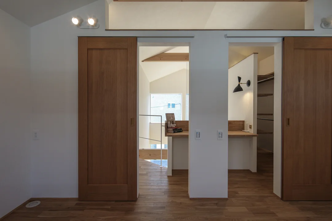 2枚の横並び引き戸が開いており、その向こうの造り付け机が見える。机は2階廊下にあり、吹抜部分の窓が奥に見える