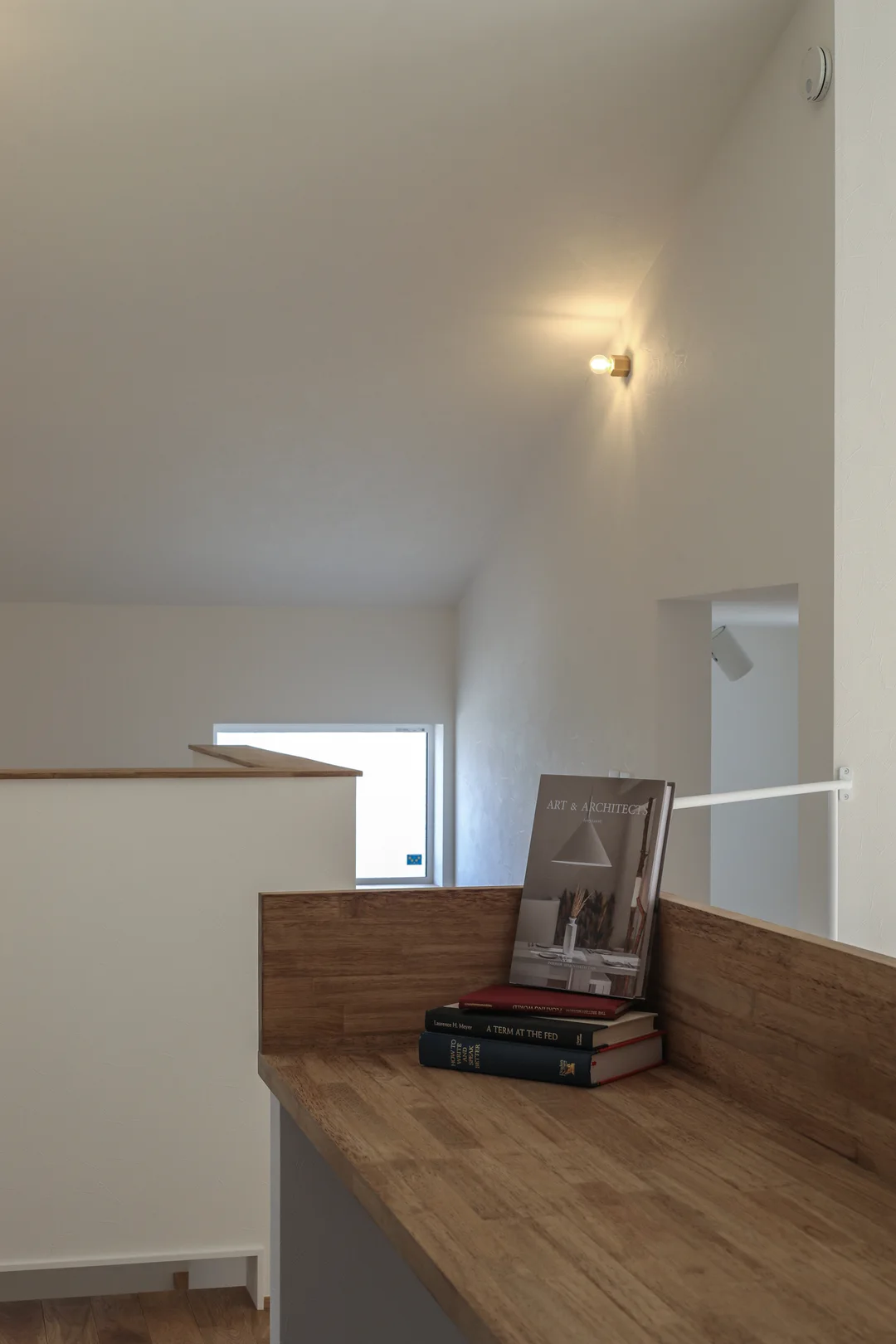 手前に造り付け机、奥に階段ホール。壁に照明