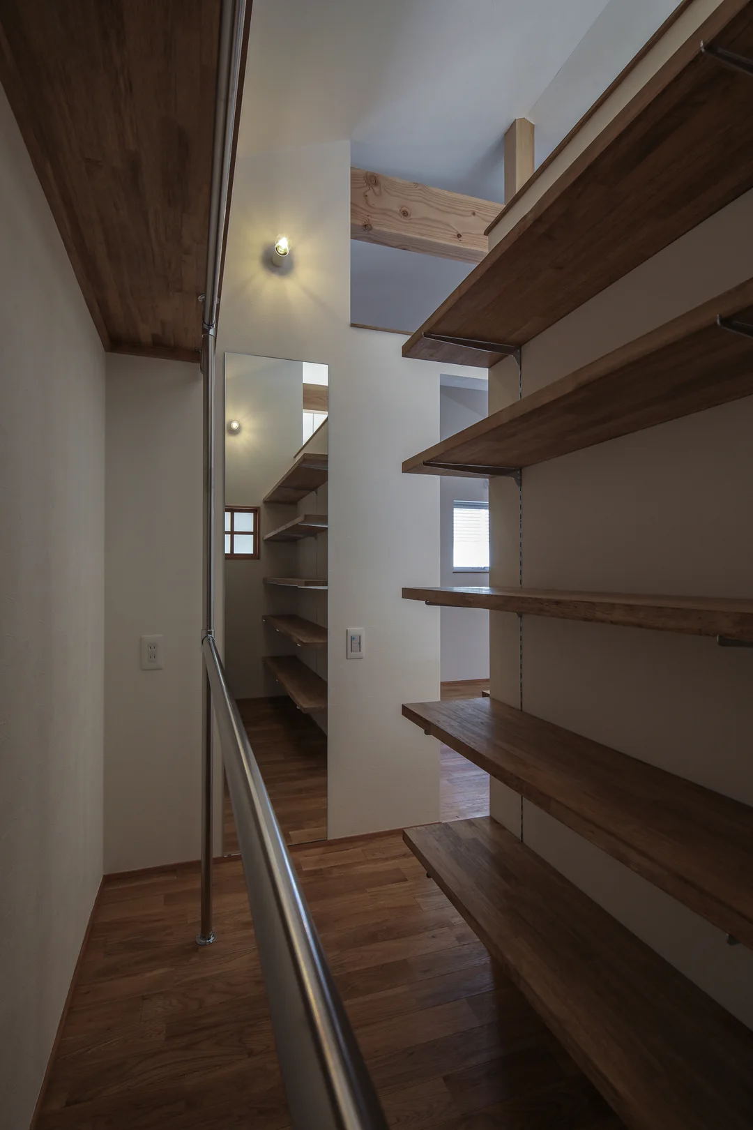 右の壁に5枚の棚板が並ぶ。板の長さは2mほど。左の壁には筒状のハンガーバー。ハンガーバーの上部に棚板がある。正面の壁に縦長の姿見。