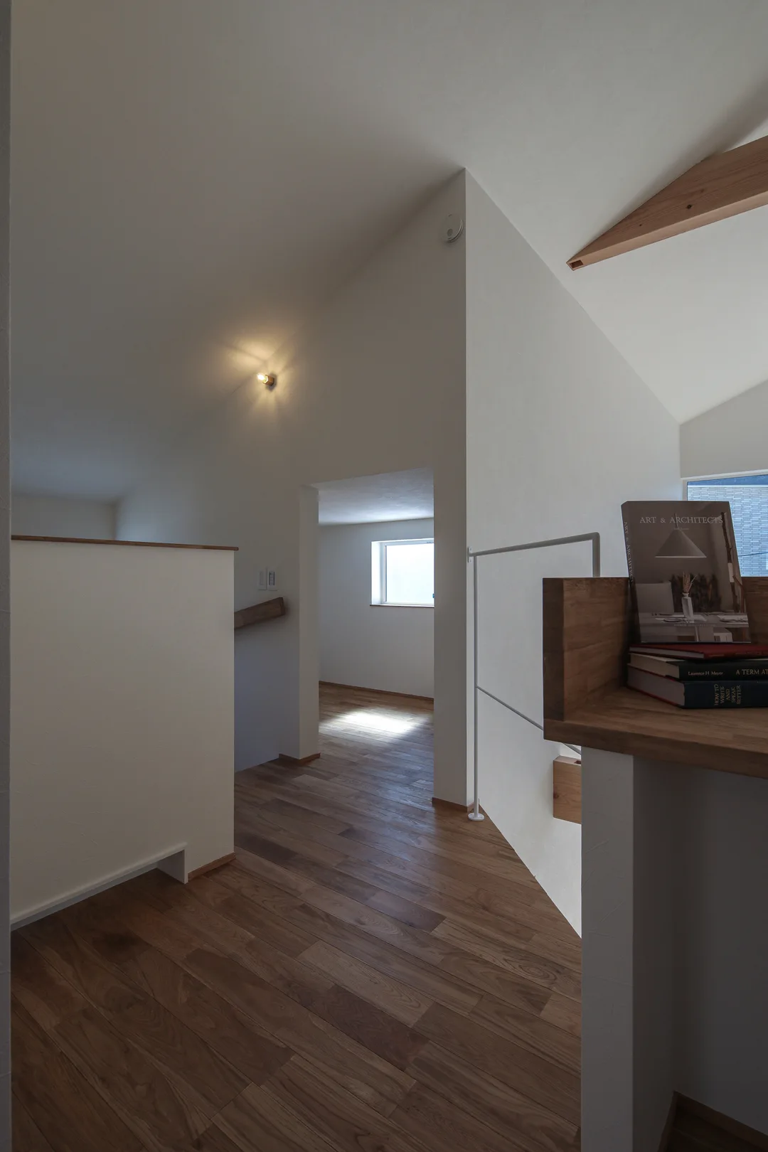 右手前に造り付けの机の一部。奥に天井の低い収納への入口。