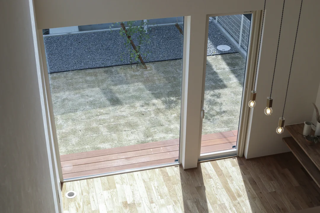 リビングと、リビング窓の外に見える芝生とウッドデッキを、2階から見ている構図