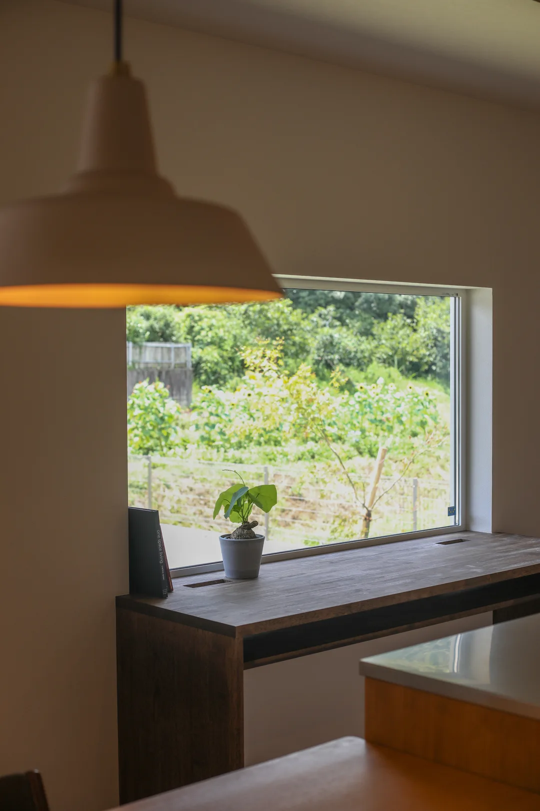 横長で1m×80cmほどの大きさの窓。窓の向こうに緑の畑。窓台がそのまま伸びて勉強机になっている。