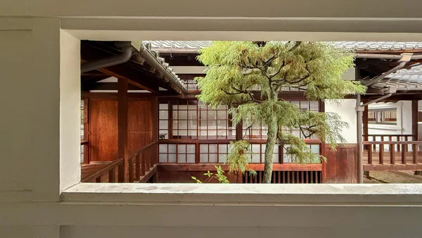 手間に白い枠があり、奥に日本家屋のような木造の建物が見える