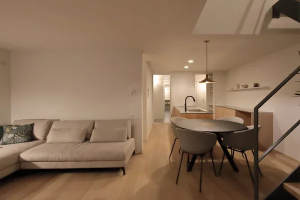 ライトグレイッシュトーンで統一された、落ち着きのあるLDK。ダイニングテーブルの奥にキッチン、手前にリビングスペースが広がる。