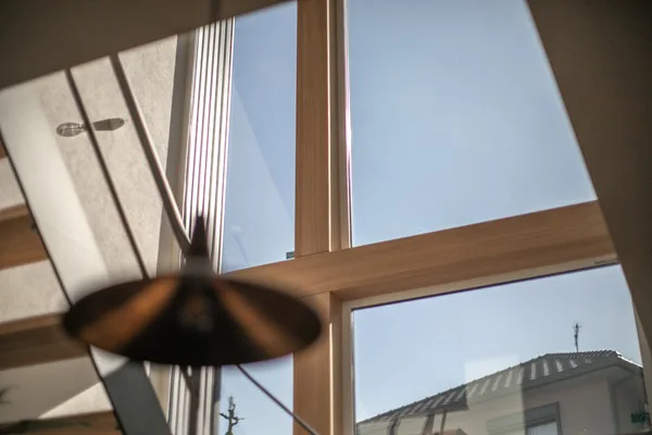 大きな窓。十字の飾りがついている。手前には真鍮のペンダントライトがある