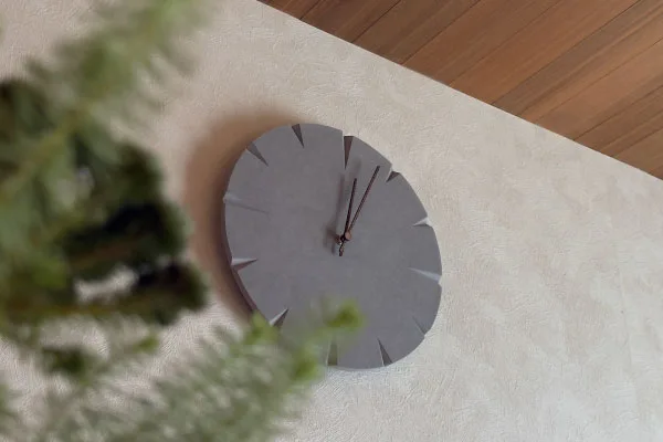 壁掛け時計。手前に植物が見える。