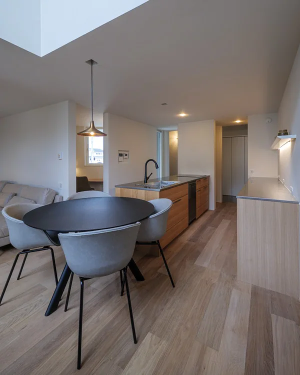 手前にダイニング、奥にキッチンがある。床はフローリングで、キッチンにも木が使われている。ダイニングには真鍮のペンダントライトがある