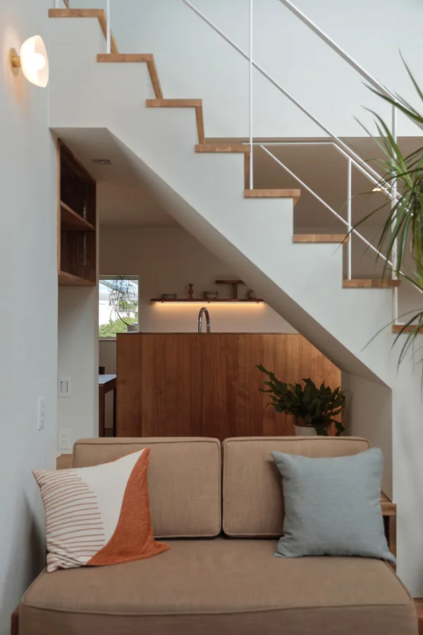 階段下のヌックとソファ。ソファの隣には観葉植物があり、ヌックを通してキッチンが見える