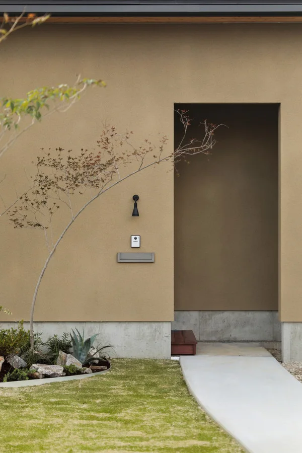 アプローチ。人を出迎えるように壁際に植栽が植わっている。