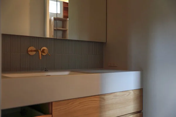 洗面台。白い台とゴールドの水栓がある