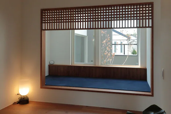 青いカーペットの床を持つヌック。奥には窓がある。手前の床にはランプが置かれている