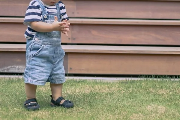 芝生の上に立つ2歳くらいの子供
