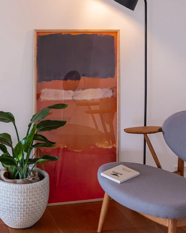 イージーチェアと、スタンドライト、観葉植物、アート作品が置かれた部屋の一角