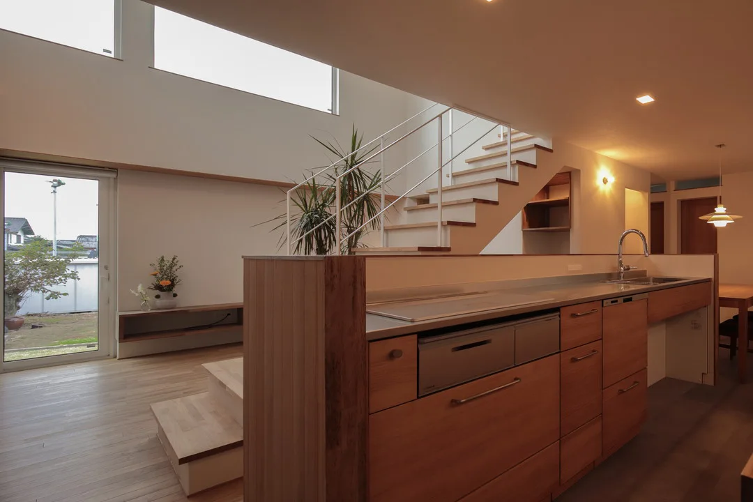 キッチン内部から見たリビングと階段。WOODONEのシステムキッチンにはIHヒーターと食洗機が備わり、大きな窓から庭が見える