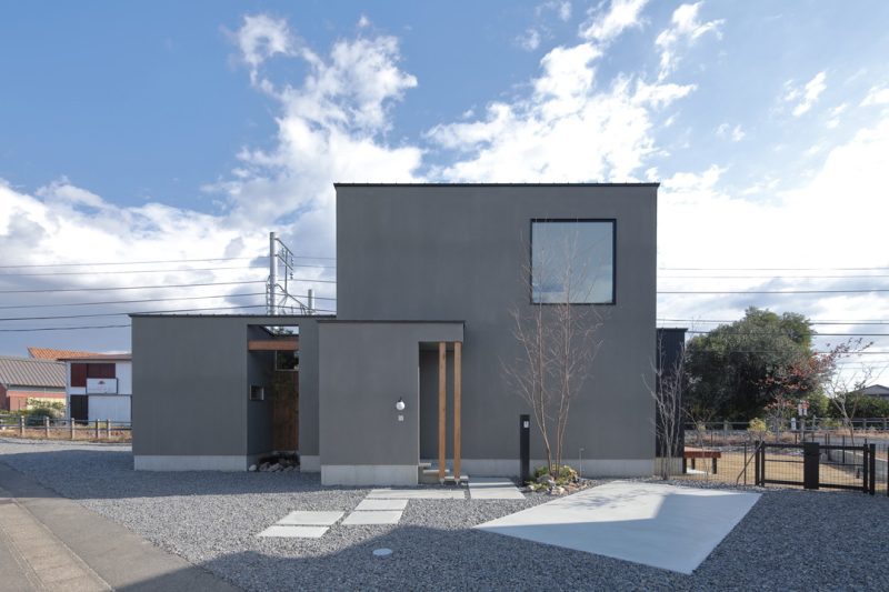 家の外観。青空、箱が2つ組み合わされたような見た目、グレーの壁の色