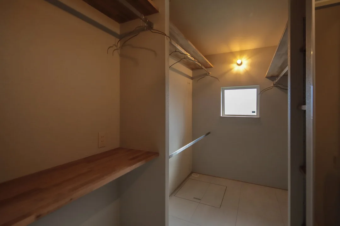 衣類を掛けられるハンガーパイプと、作業ができる木製のカウンターがある収納室。