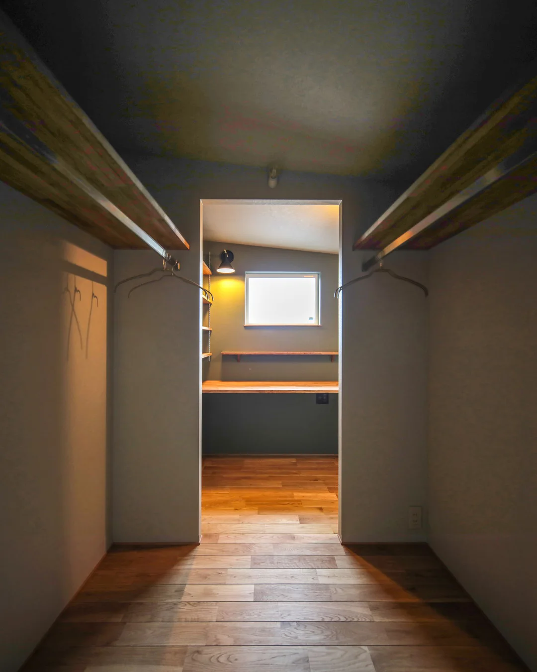 通路と兼用のウォークインクローゼット。奥に収納棚と窓のある明るい書斎デスクが見える。