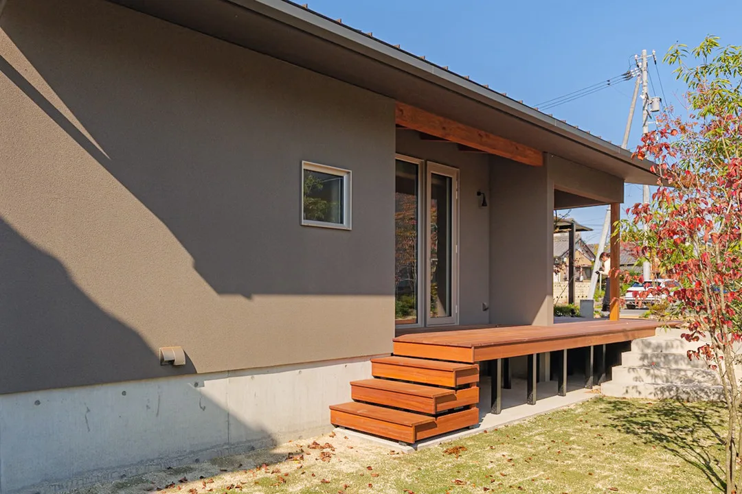 庭に面した縁側のような長いウッドデッキと、芝生へと続く木製の階段、コンクリートの階段。