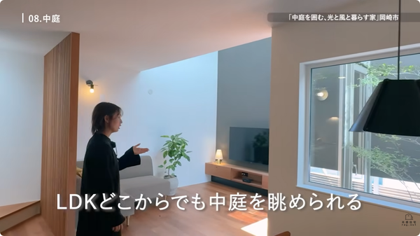 室内、女性が案内している。窓からは中庭の植栽が見える