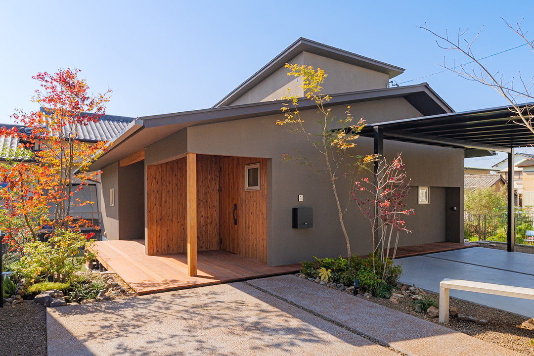 青空のしたに軒の深い家が建っている。左側に光に照らされたモミジがあり暖かな雰囲気