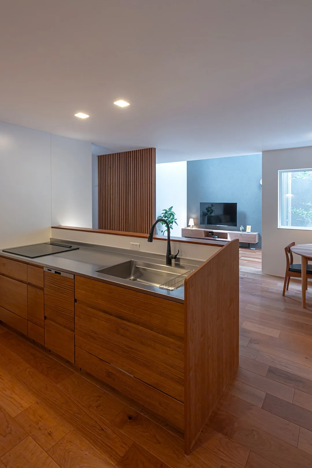 手元の広いキッチンカウンターと、その奥に広がるリビングスペース