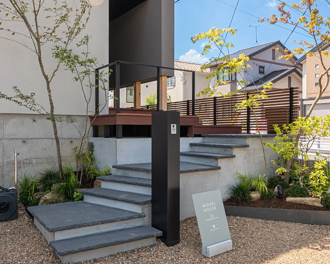 石造りの階段、ウッドデッキ、手入れされた植栽がある玄関前のアプローチ