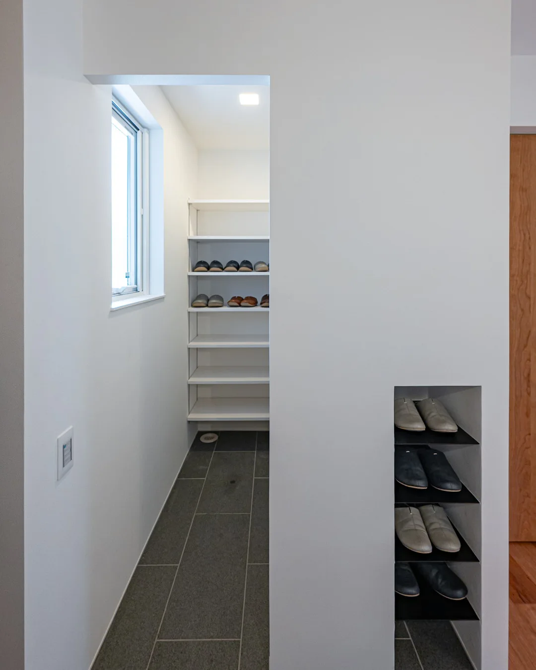 玄関横の収納スペース。靴棚とスリッパ用のニッチ、土間床の様子