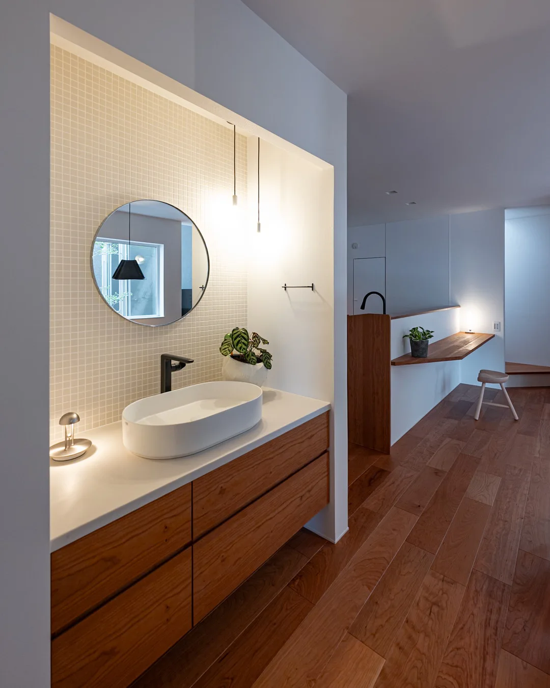 アメリカンチェリーのキャビネット、白のタイル、ペンダントライトがある洗面台