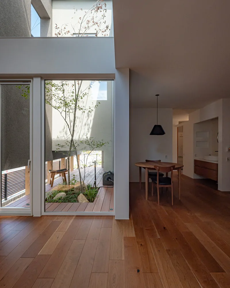大きな窓から光が差し込む、中庭のウッドデッキと植栽を望む開放的なリビングダイニング