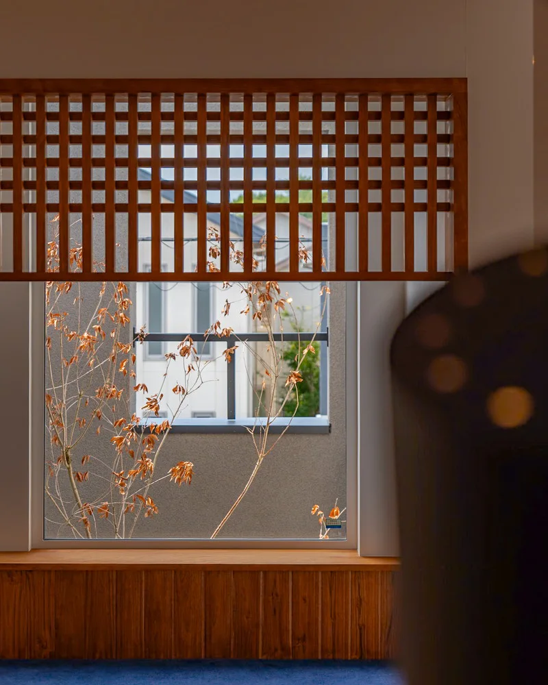木製の格子飾りがアクセントになった窓と、外の紅葉した木々が見える広いヌック
