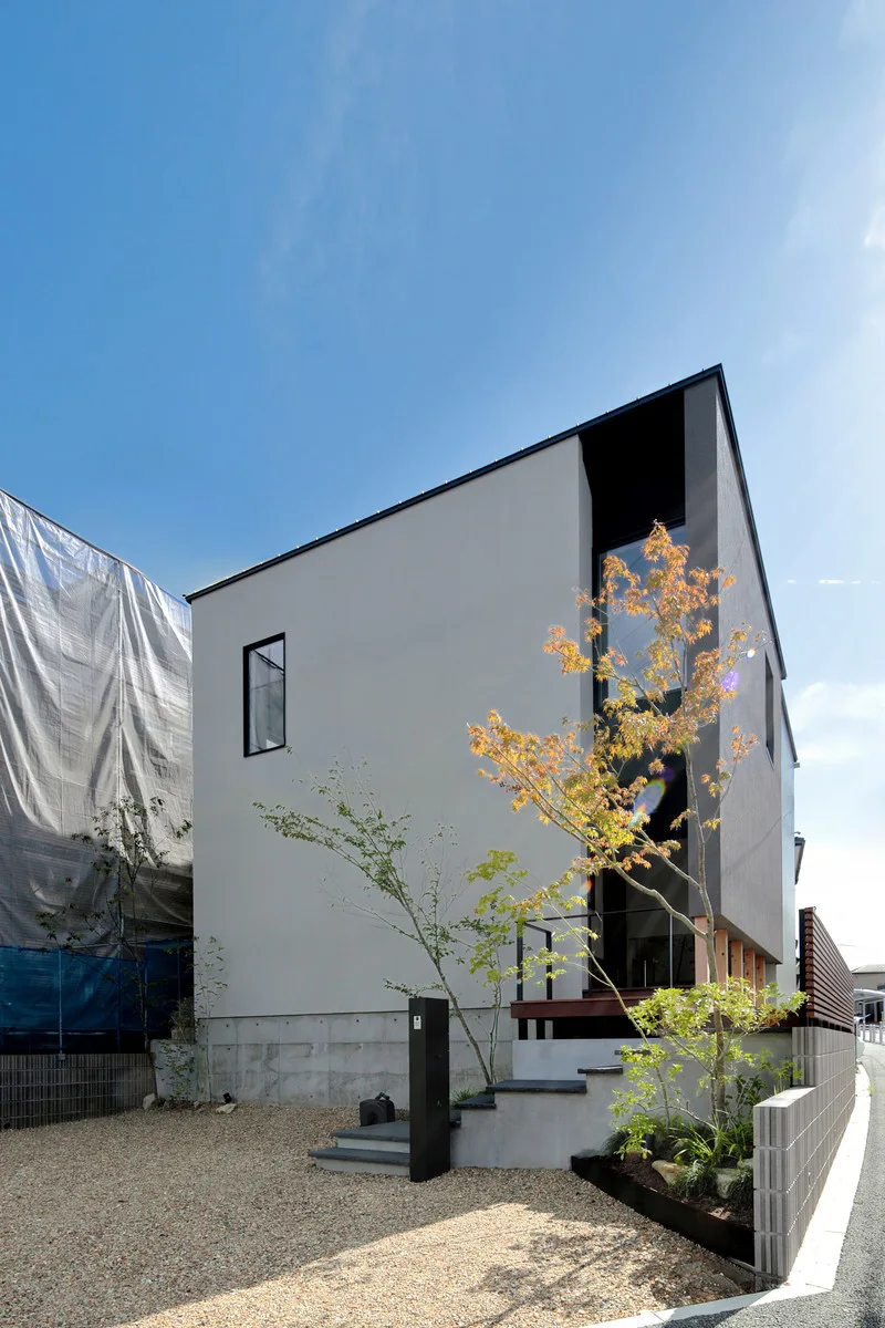 青空に映える、明るいグレーと黒のコントラストがスタイリッシュなモダンデザインの住宅外観