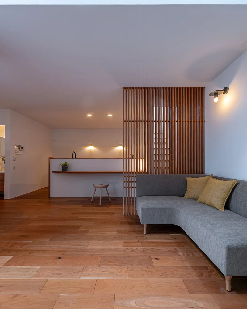 ゆったりとしたグレーのソファと、空間を緩やかに仕切る木製格子のあるリビング