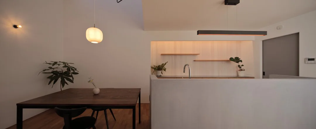 丸いペンダントライトが照らすダイニングと、間接照明がアクセントになったキッチンの背面収納